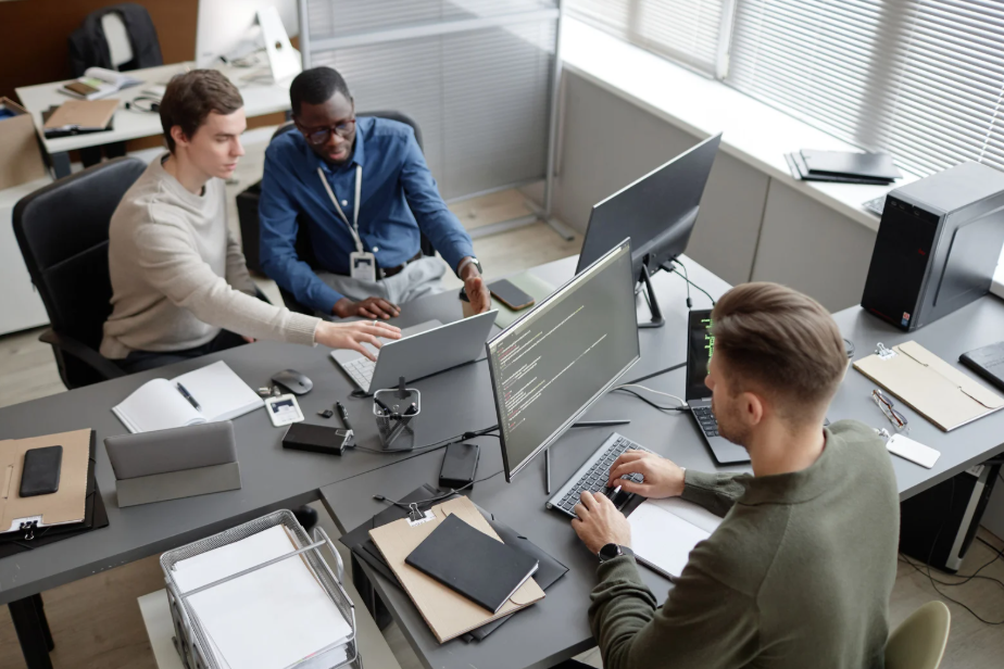 three men work at computers in an office setting